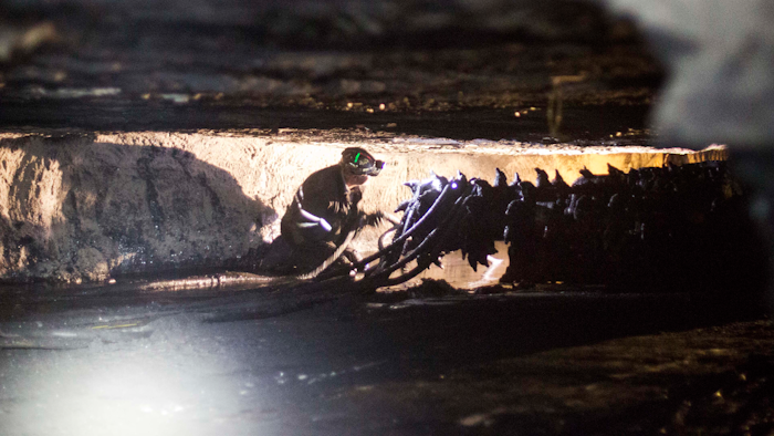 Coal miner Scott Tiller works next to a drill in an underground coal mine roughly 40 inches high in Welch, West Virginia.