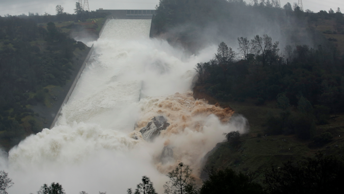 In this Feb. 9, 2017 file photo, water flows through a break in the wall of the Oroville Dam spillway in Oroville, Calif. One year after the closest thing to disaster at a major U.S. dam in a generation, federal dam regulators say they are looking hard at how they overlooked the built-in weaknesses of old dams like California's Oroville Dam for decades, and expect dam managers around the country to study their old dams and organizations equally hard.