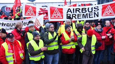 Airbus employees gather in front of the company in Bremen, northern Germany, during a strike in Bremen, Germany, Friday, Feb. 2, 2018. The union is seeking a 6-percent pay increase and the right to reduce work weeks to 28 hours for up to two years, with a guarantee that workers can return to regular hours.