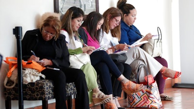 In this Tuesday, Jan. 30, 2018, photo, women fill out job applications at a JobNewsUSA job fair in Miami Lakes, Fla. The Labor Department reports on job openings and labor turnover for December, on Tuesday, Feb. 6.