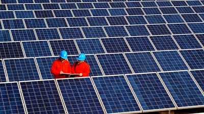 In this Feb. 7, 2012, file photo, workers check solar panels at a solar power station on a factory roof in Changxing in eastern China's Zhejiang province. One of China's biggest makers of solar panels said Tuesday, Feb. 6, 2018, that it will invest $309 million to expand manufacturing in India to guard against what it said is a rising threat of import controls in the United States and other markets.