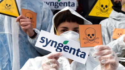 In this April 6, 2017, file photo, activists of the Basel political action committee 'March against Monsanto and Syngenta' protest in front of the Syngenta headquarters against the acquisition of Syngenta by the Chinese company ChemChina, in Basel, Switzerland. After a February 2018 announcement, critics are blasting the U.S. Environmental Protection Agency for dramatically lowering a fine on agribusiness company Syngenta for violations of pesticide regulations.