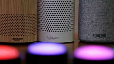 In this Sept. 27, 2017, file photo, Amazon Echo and Echo Plus devices, behind, sit near illuminated Echo Button devices during an event announcing several new Amazon products by the company in Seattle. Amazon is expanding its home-security business by buying Ring, the maker of Wi-Fi-connected doorbells. The deal comes months after the online retailer started selling its own Wi-Fi-connected indoor security cameras, which work with its voice-assistant Alexa.