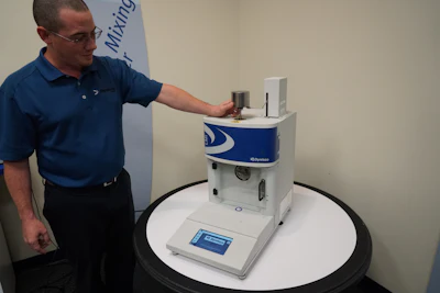 Dave Azevedo, Global Support Manager, sets a weight on the piston assembly of a Dynisco Laboratory Melt Indexer at their Franklin, MA facility.