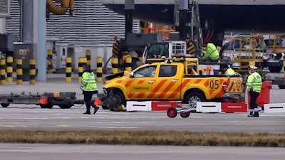 Emergency personnel attend to one of the vehicles involved in a crash at Heathrow Airport, London on Wednesday Feb. 14, 2018. London's Heathrow Airport says two men have been injured after a 'serious accident involving two vehicles' on the airfield. The airport says it is working with police to investigate the accident, which did not involve any passengers.