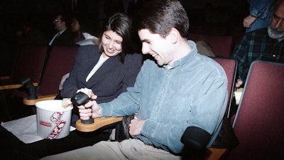 Moviegoers familiarize themselves with the joystick that will allow them to interact with the film ‘I’m Your Man’ during its premiere on Dec. 16, 1992.