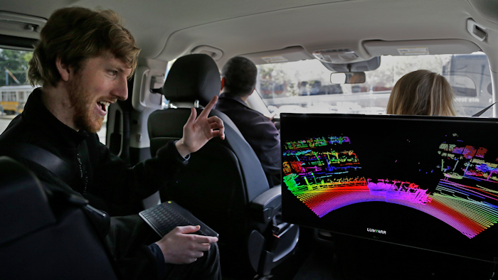 In this April 10, 2017, file photo, Luminar CEO Austin Russell gestures while looking at a 3D lidar map on a demonstration drive in San Francisco. Smaller versions of those spinning 360-degree mechanical laser sensors that sit atop self-driving cars are coming to mainstream vehicles. The lasers, called Lidar for Light Detection and Ranging, can see far-off objects in the dark, in bad weather, and in great detail.