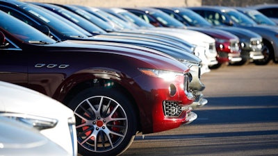 In this Sunday, Jan. 7, 2018, photograph, sun glints off the headlight housing of an unsold 2018 Maserati Levante in a long line of the high-end sports utility vehicles sitting on a dealer's lot in Highlands Ranch, Colo. On Wednesday, March 14, 2018, the Commerce Department releases U.S. retail sales data for February.