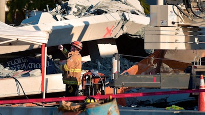 A Miami-Dade Fire Rescue firefighter takes pictures after a brand new, 950-ton pedestrian bridge collapsed in front of Florida International University, Thursday, March 15, 2018, in Miami. Florida officials said Thursday that several people have been found dead in the rubble of a collapsed South Florida pedestrian bridge where the frantic search for any survivors continued past nightfall.