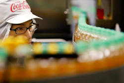 In this Nov. 17, 2016, file photo, a worker watches a product line at Coca-Cola Ebina plant in Ebina, Kanagawa Prefecture, near Tokyo. Coca-Cola may be getting into the booze business again by developing a bubbly alcoholic drink in Japan. The soda maker, best known for Coke, Sprite and Fanta, says it’s experimenting with a canned beverage that would be a mix of sparkling water and an alcoholic Japanese drink.