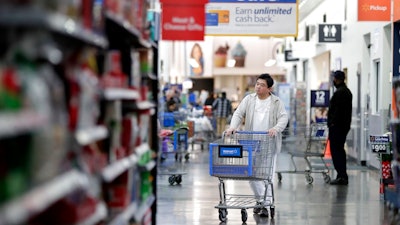 In this Nov. 9, 2017, file photo, a man pushes a cart while shopping at a Walmart store in North Bergen, N.J. On Thursday, March 29, 2018, the Commerce Department issues its February report on consumer spending.