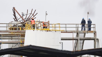 People stand the site of an explosion in a chemical plant in Kralupy nad Vltavou, Czech Republic, Thursday, March 22, 2018. Vladimira Kerekova, spokeswoman for the regional firefighters, says an explosion in a chemical factory, north of Prague, the Czech Republic has killed six people and injured an unspecified number.