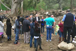 In this photo provided by G.F.Bunting survivor and co-plaintiff Lalo Barajas, center, whose partner Peter Fleurat was killed during devastating debris flows in January at their home, speaks at the site in Montecito, Calif, Thursday, March 29, 2018. Attorneys from left, Joseph Liebman, Geoff Spreter, Peter Bezerk, and Alex Robertson, right, announced the filing of a wrongful-death lawsuit by Barajas and Fleurat's siblings claiming Southern California Edison transformers ignited California's largest-ever wildfire in December. The suit says the blaze could have been prevented and the debris flows wouldn't have happened as a result.