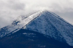 In this Feb. 17, 2010, file photo, the snowcapped Cabinet Mountains tower over the lush Kootenai River Valley outside of Libby, Mont. Montana regulators say an Idaho company proposing two mines beneath the Cabinet Mountains Wilderness is in violation of a state law that prohibits individuals from starting new mines if they haven't cleaned up old ones.