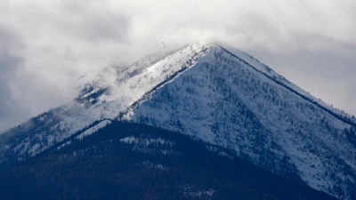 In this Feb. 17, 2010, file photo, the snowcapped Cabinet Mountains tower over the lush Kootenai River Valley outside of Libby, Mont. Montana regulators say an Idaho company proposing two mines beneath the Cabinet Mountains Wilderness is in violation of a state law that prohibits individuals from starting new mines if they haven't cleaned up old ones.