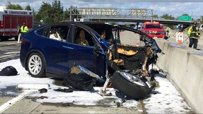 In this Friday March 23, 2018 photo provided by KTVU, emergency personnel work a the scene where a Tesla electric SUV crashed into a barrier on U.S. Highway 101 in Mountain View, Calif. The National Transportation Safety Board has sent two investigators to look into a fatal crash and fire Friday in California that involved a Tesla electric SUV. The agency says on Twitter that it's not clear whether the Tesla Model X was operating on its semi-autonomous control system called Autopilot at the time. Investigators will study the fire that broke out after the crash.