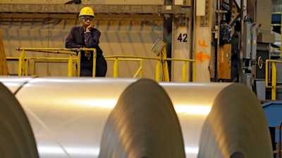 In this Feb. 15, 2013, file photo, an employee looks on from behind coils of steel as acting Secretary of Labor Seth Harris speaks to workers after a tour of ArcelorMittal Steel's hot dip galvanizing line in Cuyahoga Heights, Ohio. President Donald Trump’s tariffs are expected to raise prices for steel and aluminum in this country. That will help domestic producers and could create several hundred new steelworker jobs.