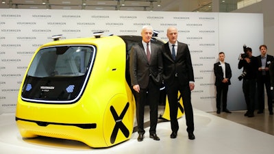 VW group CEO Matthias Mueller, left, and CFO Frank Witter, right, pose in front of a self driving concept car prior to the annual media conference of the Volkswagen group, in Berlin, Germany, Tuesday, March 13, 2018.