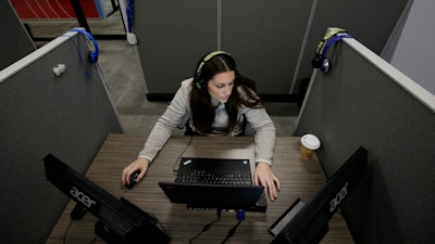 In this Nov. 8, 2017, photo Jessica McShane, an employee at Interactions Corp., monitors person-to-computer communications, helping computers understand what a human is saying, in the 'intent analysis' room at the company's headquarters in Franklin, Mass. When a computer can’t make out a customer call to the Hyatt Hotels chain, an audio snippet is sent to AI-powered call center Interactions. There, while the customer waits on the phone, an analyst transcribes everything from misheard numbers to profanities and quickly directs the computer how to respond.