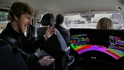 In this April 10, 2017, file photo, Luminar CEO Austin Russell gestures while looking at a 3D lidar map on a demonstration drive in San Francisco. Smaller versions of those spinning 360-degree mechanical laser sensors that sit atop self-driving cars are coming to mainstream vehicles. The lasers, called Lidar for Light Detection and Ranging, can see far-off objects in the dark, in bad weather, and in great detail.