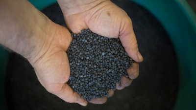 In this Tuesday, March 13, 2018 photo, a worker holds bio-based thermoplastic composite made from substantially unsorted municipal solid waste material in the UBQ factory in Kibbutz Zeelim. Israeli start-up UBQ says its innovative method to convert garbage into plastics, five years in the making, will revolutionize waste management worldwide and make landfills obsolete.