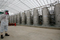 In this Nov. 12, 2014, file photo, a Tokyo Electric Power Co. (TEPCO) official wearing a radioactive protective gear stands in front of Advanced Liquid Processing Systems during a press tour at the Fukushima Dai-ichi nuclear power plant in Okuma, Fukushima Prefecture, northeastern Japan. A government-commissioned group of experts concluded Wednesday, March 7, 2018 that a costly underground ice wall is only partially effective in reducing the ever-growing amount of contaminated water at the destroyed Fukushima nuclear plant, and that other measures are needed as well.