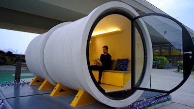 In this Tuesday, March 13, 2018, photo, architect James Law sits at an OPod tube house in Hong Kong's industrial area of Kwun Tong. Hong Kong’s notoriously expensive housing makes owning an affordable home a pipe dream for many residents. But the local architect proposed a novel idea to help alleviate the problem: building stylish micro-apartments inside giant concrete drainage pipes.