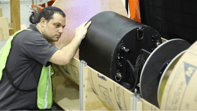 David Kohanbash, senior research programmer at the Carnegie Mellon University Robotics Institute, prepares the RadPiper robot for a test in a mockup pipe. The robot is designed to measure radiation levels within processing pipes used for uranium enrichment.