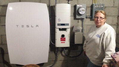Rhonda ‘Honey’ Phillips, alongside the Tesla Powerwall battery and inverter connected to solar panels in her Middletown Springs, Vt., yard.