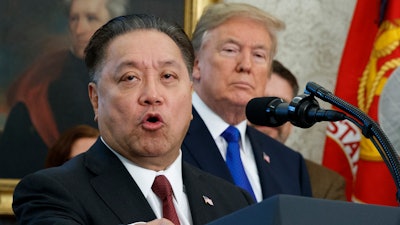 In this Thursday, Nov. 2, 2017, file photo, Broadcom CEO Hock Tan speaks while U.S. President Donald Trump listens, in background, during an event at the White House in Washington, to announce the company is moving its global headquarters to the United States. In a decision announced Monday, March 12, 2018, Trump is blocking Singapore chipmaker Broadcom from pursuing a hostile takeover of U.S. rival Qualcomm on the grounds that the combination would threaten national security.