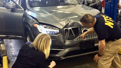 In this March 20, 2018, photo provided by the National Transportation Safety Board, investigators examine a driverless Uber SUV that fatally struck a woman in Tempe, Ariz. The fatality prompted Uber to suspend all road-testing of such autos in the Phoenix area, Pittsburgh, San Francisco and Toronto.