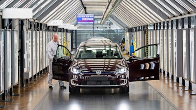 Roland Schulz makes the final check of an e-Golf electric car in the so-called light tunnel in the German car manufacturer Volkswagen's Transparent Factory in Dresden, Germany, Monday, March 5, 2018.