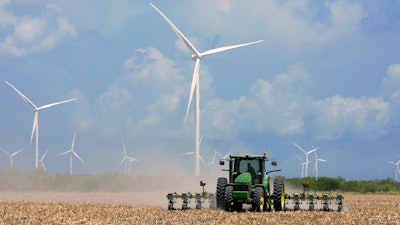 In this Aug. 17, 2015, file photo, a farmer plows his recently harvested field under wind turbines in the agricultural area north of Rio Hondo, Texas, near the New Mexico border. New Mexico regulators on Wednesday, March 21, 2018, approved a $1.6 billion plan that calls for building two massive wind farms along the Texas-New Mexico border.