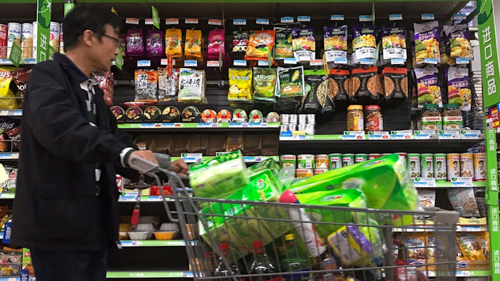 A man pushes a shopping cart past a display of nuts imported from the United States and other countries at a supermarket in Beijing, Monday, April 2, 2018. China raised import duties on a $3 billion list of U.S. pork, fruit and other products Monday in an escalating tariff dispute with President Donald Trump that companies worry might depress global commerce.