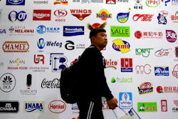 In this April 12, 2018, photo, a man walks by a billboard displaying a Chinese company developed packaging machinery for local and foreign food and beverage companies at the International soybean exhibition in Shanghai. Chinese soybean farmers, importers and processers say they are unconcerned about potential Chinese tariffs on American soybeans in an escalating dispute with the administration of President Donald Trump over trade and technology.