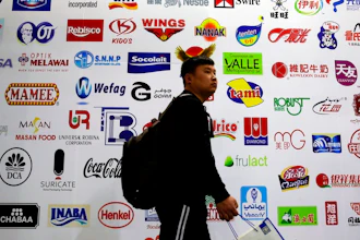In this April 12, 2018, photo, a man walks by a billboard displaying a Chinese company developed packaging machinery for local and foreign food and beverage companies at the International soybean exhibition in Shanghai. Chinese soybean farmers, importers and processers say they are unconcerned about potential Chinese tariffs on American soybeans in an escalating dispute with the administration of President Donald Trump over trade and technology.