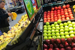 A man chooses bananas near imported apples from the United States at a supermarket in Beijing, Monday, April 2, 2018. China raised import duties on a $3 billion list of U.S. pork, fruit and other products Monday in an escalating tariff dispute with President Donald Trump that companies worry might depress global commerce.