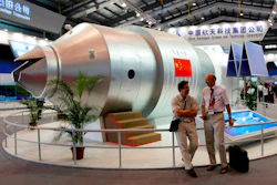 In this Nov. 16, 2010 file photo, visitors sit beside a model of China's Tiangong-1 space station at the 8th China International Aviation and Aerospace Exhibition in Zhuhai in southern China's Guangdong Province. China’s defunct Tiangong 1 space station is expected to re-enter Earth’s atmosphere within the next day. The European Space Agency forecast Sunday April 1, 2018 the station will re-enter sometime between Sunday night and early Monday morning GMT.