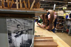 In this Friday, March 23, 2018 photo, a photo of Johnny Cash hangs near a luthier assembling the rosewood sides of a guitar at C. F. Martin and Co., in Nazareth, Pa. The cost and hassle of the new regulations on rosewood have caused some guitar makers to shift away from it. Martin stopped using it on most guitars produced in Mexico and the models made in the U.S. that cost less than $3,000.