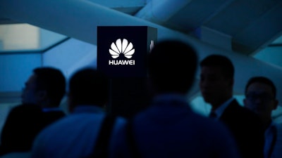 In this May 26, 2016, photo, attendees stand near a pillar with the Huawei logo during a launch event for the Huawei Matebook in Beijing. As trade disputes simmer, Chinese telecommunications giant Huawei, the No. 3 smartphone brand, is shifting its growth efforts toward Europe and Asia in the face of mounting obstacles in the U.S. market.