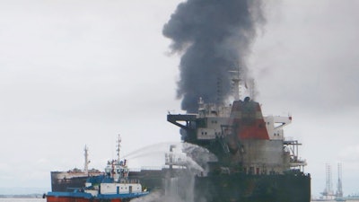 In this Saturday, March 31, 2018, photo, a tug boat tries to extinguish fire from a burning oil tanker in Balikpapan, Indonesia. Waters off an Indonesian port city reek like a gas station after an oil spill and fire that killed four people over the weekend, an official said Wednesday, April 4.