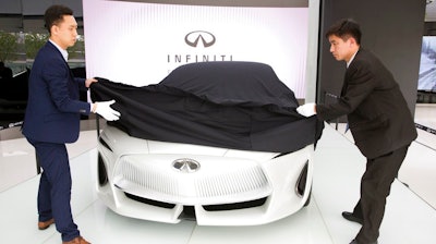 n this April 19, 2018, photo, workers remove the veil from the Infiniti electric concept sedan at a showroom ahead of the Auto China 2018 to be held in Beijing, China. Auto China 2018, the biggest global auto show of the year, showcases China's ambitions to become a leader in electric cars and the industry's multibillion-dollar scramble to roll out models that appeal to price-conscious but demanding Chinese drivers.