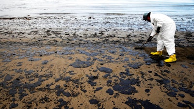 In this May 21, 2015, file photo, a worker removes oil from sand at Refugio State Beach, north of Goleta, Calif. Jurors being selected Thursday, April 19, 2018, in Santa Barbara County Superior Court will determine if Plains All American Pipeline, a Texas company that operated an oil pipeline that spilled crude along the California three years ago, broke any laws.