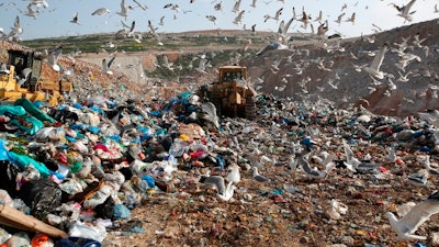 In this Wednesday, Feb. 2, 2018 file photo, earthmovers push mountains of garbage as seagulls fly over the country's largest landfill at Fyli on the outskirts of Athens. The British government is planning a consultation about a possible bill to end the use of plastic straws, drink stirrers and cotton buds - and is urging other Commonwealth nations to ban the practice as well. Prime Minister Theresa May said Thursday, April 19, 2018 that “plastic waste is one of the greatest environmental challenges facing the world.”