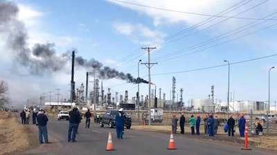 This photo provided by KQDS_FOX21 in Duluth, Minn., shows vehicles and personnel outside the Husky Energy oil refinery Thursday morning, April 26, 2018, after a tank containing crude oil or asphalt exploded at the large refinery in Superior, Wis. Authorities say several people were injured. The flame at the right is a normal part of refinery operations.