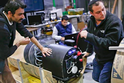 In this photo made on Wednesday, April 4, 2018, Mohammad Mousaei, top, and David Kohandash work on the RadPiper robot in the robotics institute at Carnegie-Mellon University in Pittsburgh. The mechanism is designed to measure potentially hazardous radiation is intended to go through pipes at a former uranium plant being cleaned up in southern Ohio.