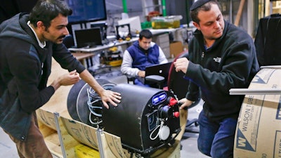 In this photo made on Wednesday, April 4, 2018, Mohammad Mousaei, top, and David Kohandash work on the RadPiper robot in the robotics institute at Carnegie-Mellon University in Pittsburgh. The mechanism is designed to measure potentially hazardous radiation is intended to go through pipes at a former uranium plant being cleaned up in southern Ohio.
