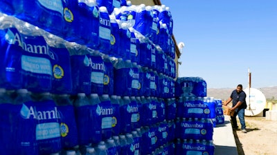 Tommy Gutierrez, a Paiute tribe member, helps load up some of the thousands of plastic water bottles that are distributed weekly to the Yerington Paiute tribe in Yerington, Nev., Friday, April 27, 2018. Atlantic Richfield, the owner of a abandoned open pit mine nearby, has suspended the normal bottled water deliveries it's been providing neighbors since tests in 2004 confirmed a plume of groundwater contaminated area wells. The move comes two months after federal regulators backed off plans to add the mine to the list of the most toxic U.S. Superfund sites.