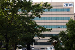 In this April 17, 2018, photo, a woman walks through the parking lot of a building hosting ZTE subsidiaries in Nanjing in eastern China's Jiangsu province. Chinese tech company ZTE said Friday, April 20, 2018, that it won't accept an 'unfair' U.S. penalty in a case involving exports of telecoms equipment to North Korea and Iran and is seeking a solution through legal channels.