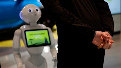 In this photo dated March 12, 2018, a guests asks robot Robby Pepper for information at the front desk of hotel in Peschiera del Garda, northern Italy. Robby Pepper, billed as Italy's first robot concierge, has been programed to answer simple guest questions in Italian, English and German, the humanoid, speaking robot will be deployed all season at a hotel on the popular Garda Lake to help relieve the desk staff of simple, repetitive questions.
